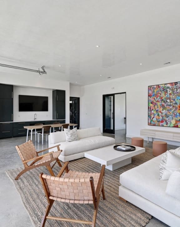 a living room with white couches and chairs and a television