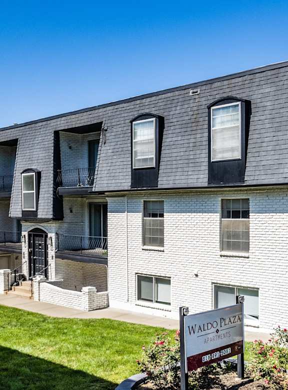 A pool in front of a building with a black fence around it.