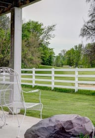 white metal chair on concrete patio facing white fence