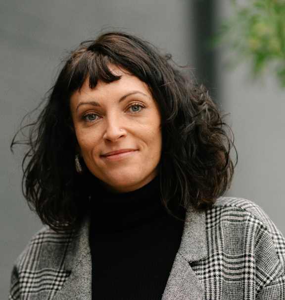 A woman with a black turtleneck and a plaid jacket.