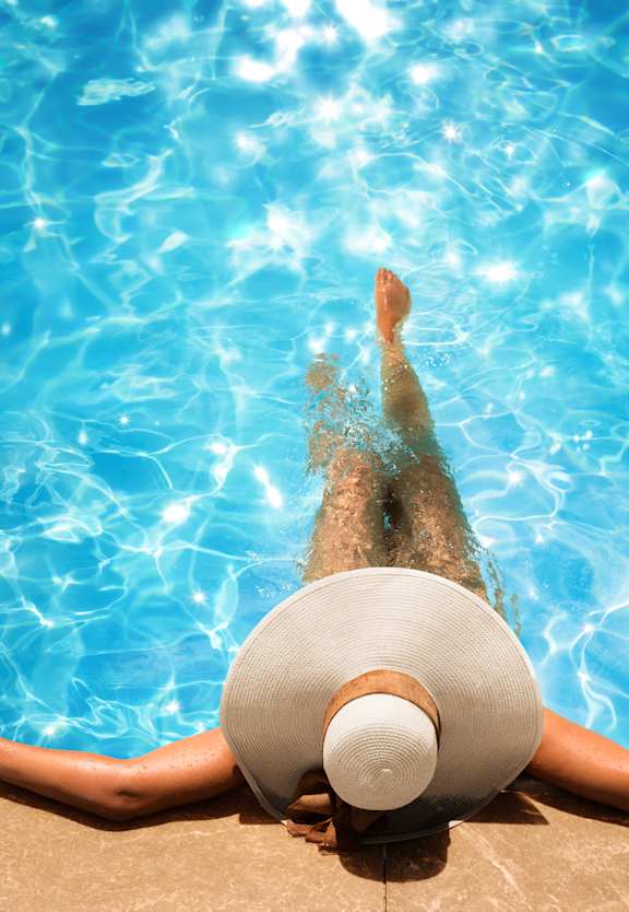 A person wearing a white hat is floating in a pool.