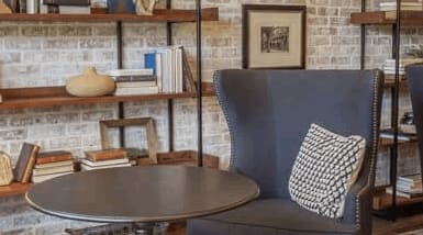 a living room with blue chairs and a table and a brick wall