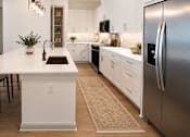 Thumbnail 35 of 40 - A modern kitchen with a white island and stainless steel appliances.