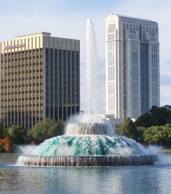 a fountain in a lake in front of tall buildings