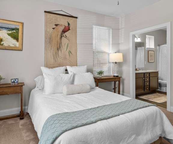 A bedroom with a large bed and a painting of a bird on the wall.