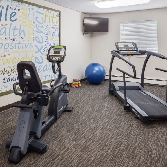 a workout room with cardio equipment and a yoga board