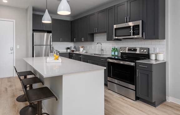 A modern kitchen with a white island and black cabinets. at The Edwin on Grand Apartments, St Louis, 63103