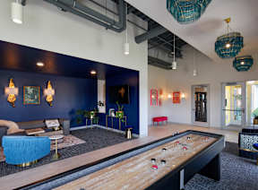 A pool table is in the middle of a room with a blue couch and a red chair.