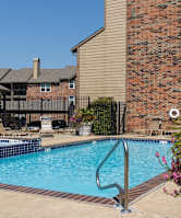 A poolside patio at Foxfire Apartments with seating and brick accents.