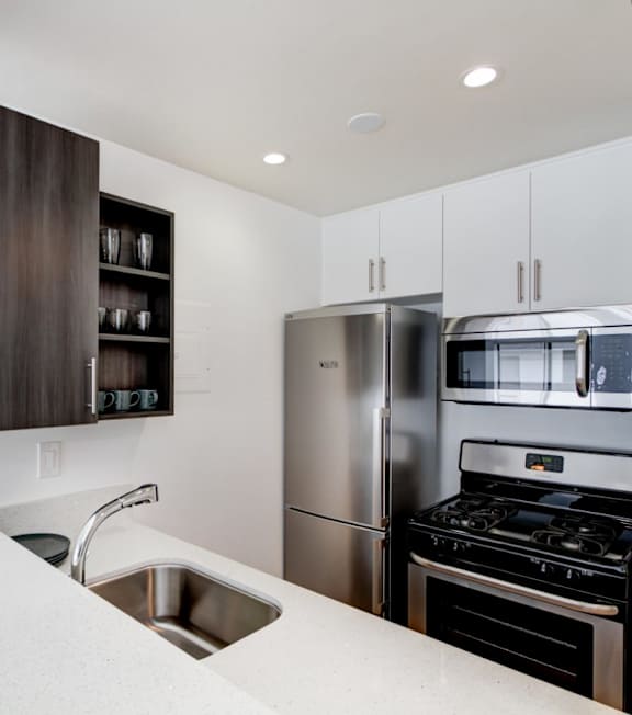 a kitchen with white cabinets and green walls at El Greco Lofts, Los Angeles, CA