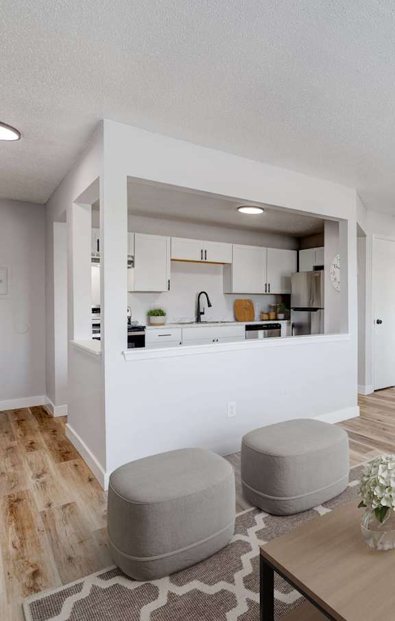 A modern living room with a kitchen in the background at The Hampton Meadows Apartments, Des Moines, Iowa