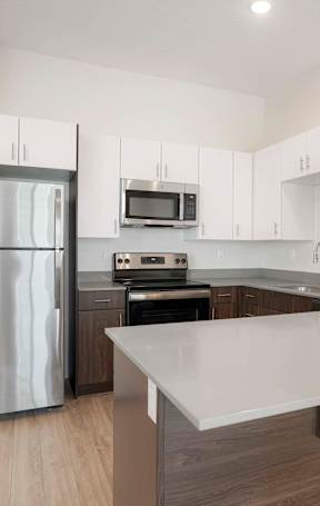 A modern kitchen with a refrigerator, microwave, oven, and sink.