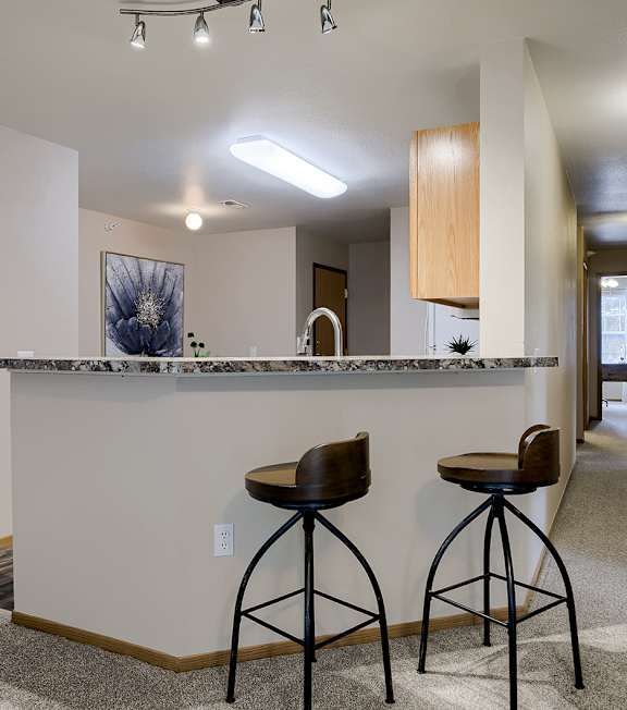 A bar area with two stools in a modern room.