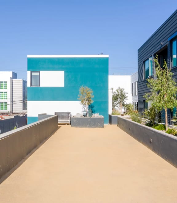 A modern building with a blue and white facade stands in the foreground of a cityscape.