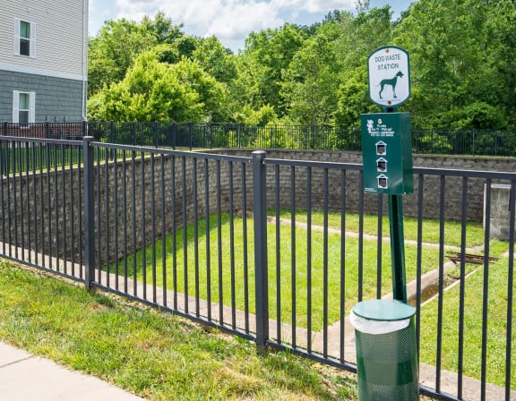 a black wrought iron fence with a green sign on it and a yard behind it
