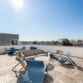 A sunny day on a wooden deck with blue chairs and a table.