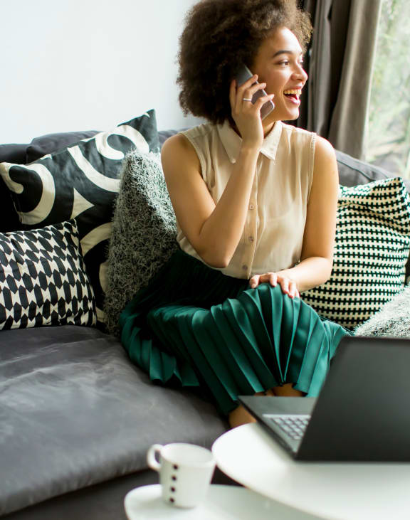 a woman sitting on a couch talking on the phone
