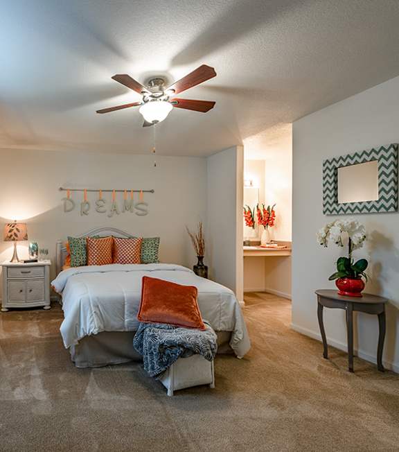 A bedroom with a bed, dresser, and ceiling fan.