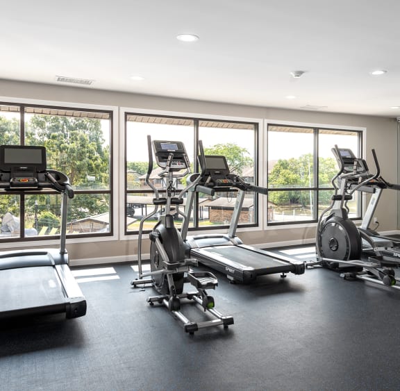 the gym has plenty of exercise equipment and windows