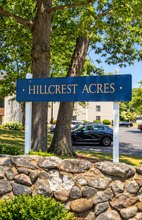 A sign that says Hillcrest Acres stands in front of a building.
