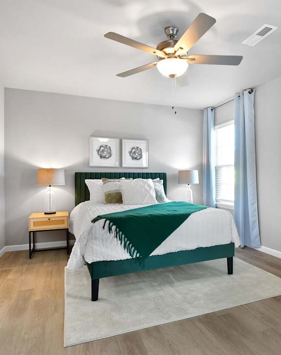 A bedroom with a bed, nightstand, and a ceiling fan.
