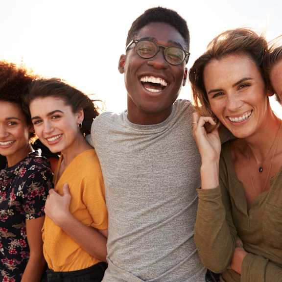 A group of five people are standing together smiling.