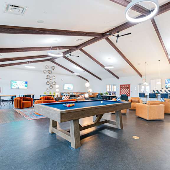 A pool table in a room with a couch and a window.