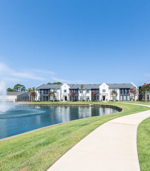 a walkway around a lake with apartments in the background at Residences at 393 North Apartments, Santa Rosa Beach, Florida