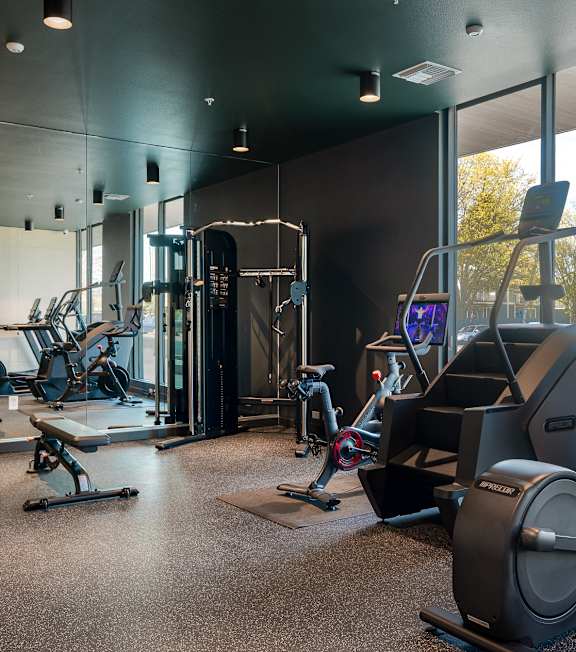 A gym with a variety of equipment including treadmills, weights, and exercise machines.