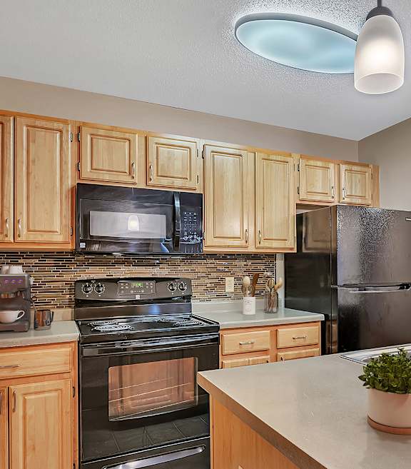 an updated kitchen with black appliances and wood cabinets
