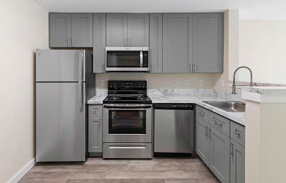 a kitchen with gray cabinets and stainless steel appliances at Excalibur Apartment Homes, Bellevue, WA, 98004