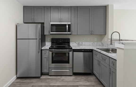 a kitchen with gray cabinets and stainless steel appliances at Excalibur, Washington, 98004