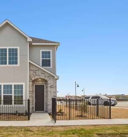 A two-story house with a black fence in front.
