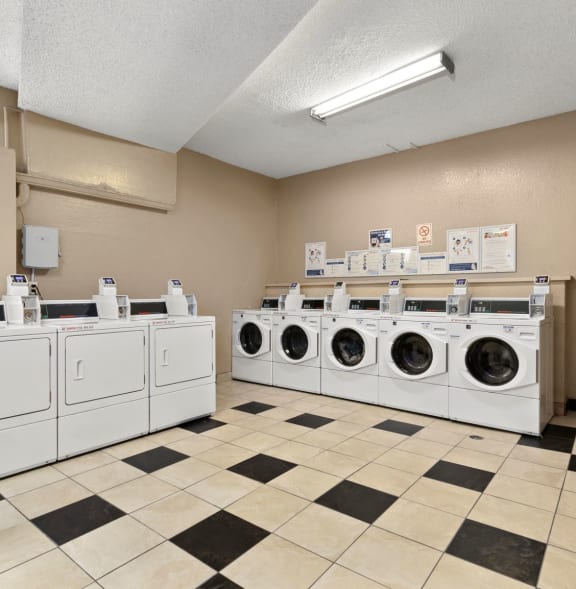 a group of washers and dryers in a laundromat with many machines