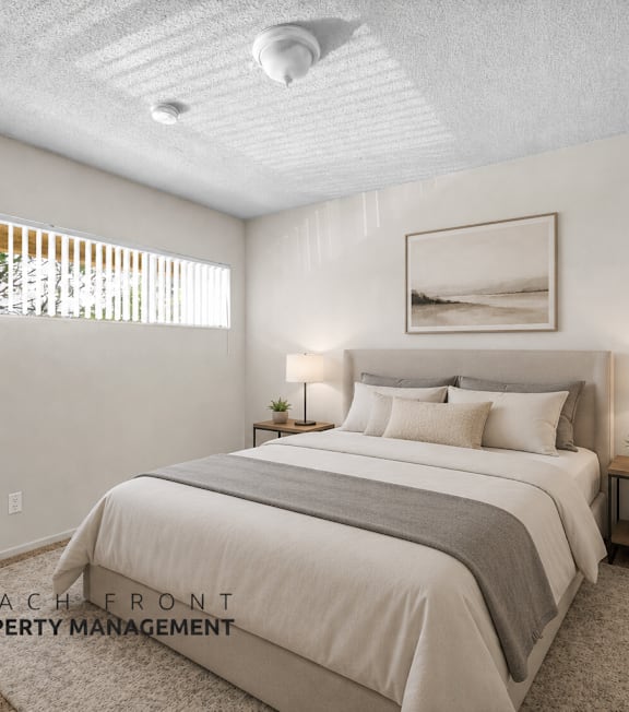 A well-lit bedroom with a large bed and a framed picture on the wall.