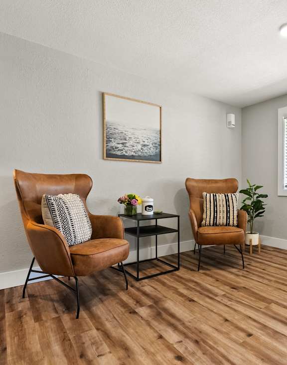 A room with two chairs and a table with a plant on it.