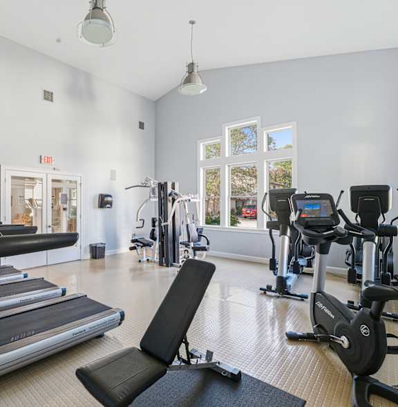 A gym with treadmills, elliptical machines, and a weight machine at Hidden Brook Apartment Homes Apartments, New Bedford, MA, 02740