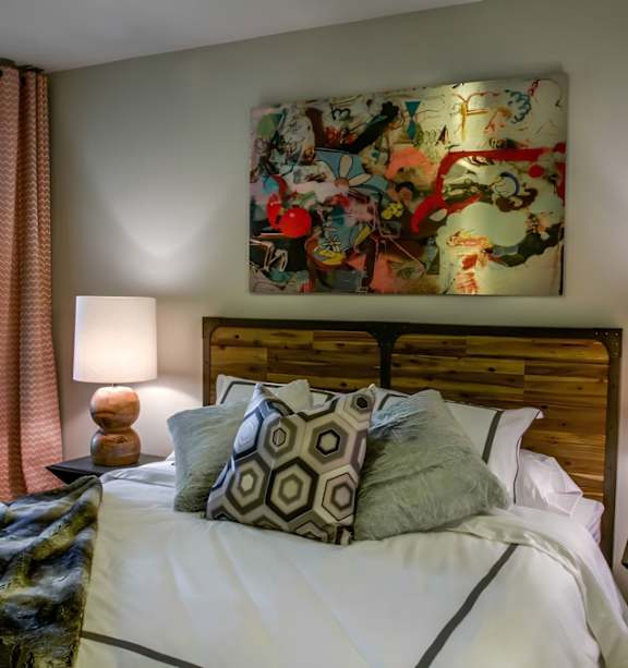 A bedroom with a large bed and a colorful painting above it.