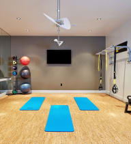 a home gym with a ceiling fan and weights and yoga mats