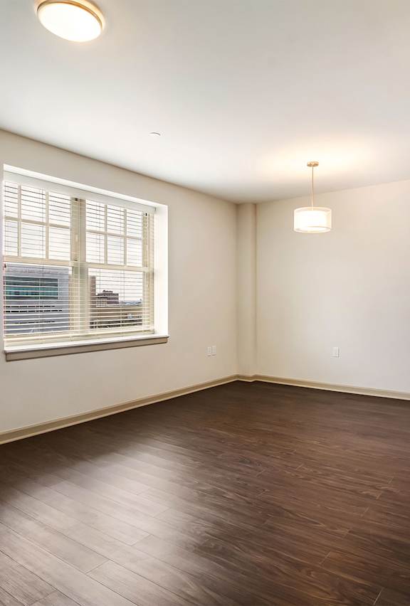 A room with wooden flooring and a window with blinds.