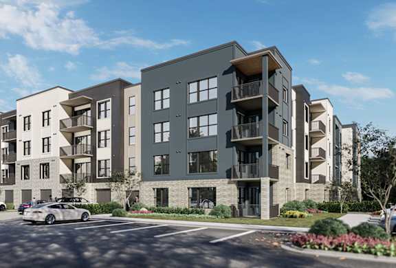 A modern apartment complex with cars parked in front.