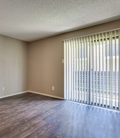 an empty living room with a large window and wood flooring at The Manhattan Apartments, Dallas, TX, 75252