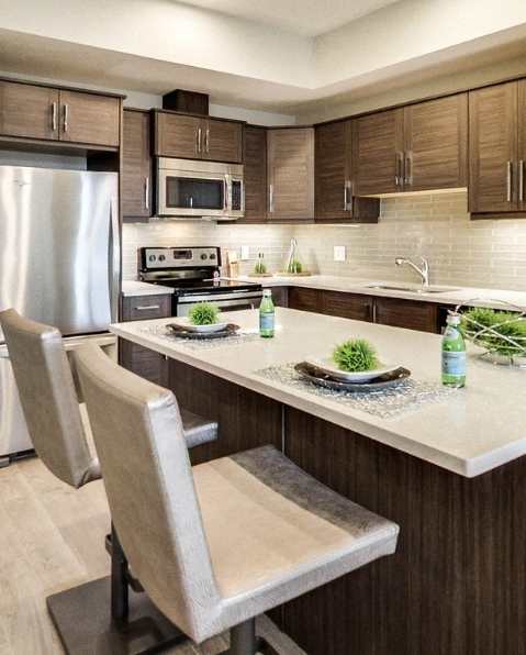 A modern kitchen with a stainless steel refrigerator and wooden flooring.