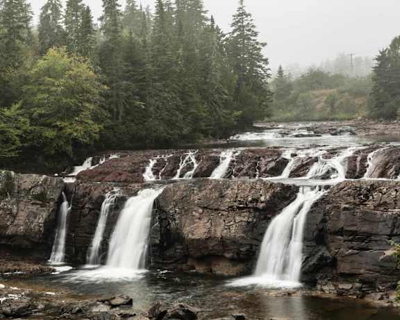 A waterfall cascades over a rocky cliff surrounded by trees.