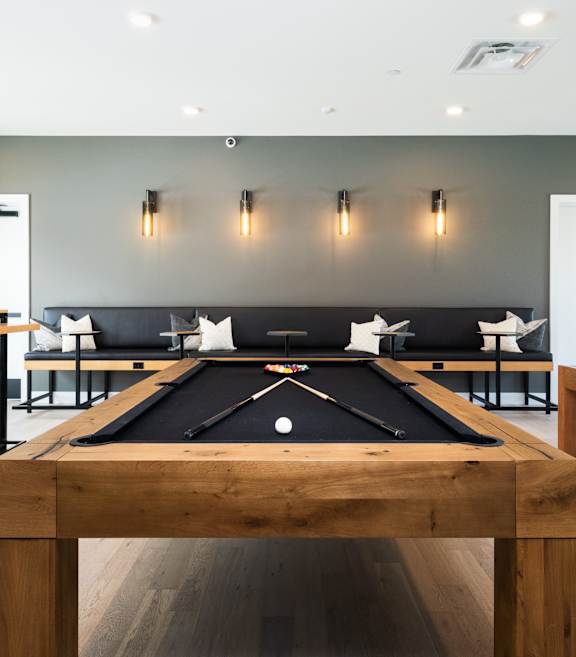 A pool table in the middle of a room with a light on the wall.
