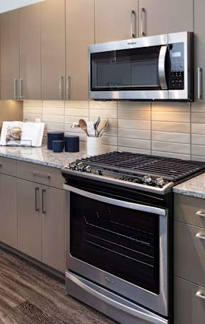 A modern kitchen with a granite countertop and stainless steel appliances.