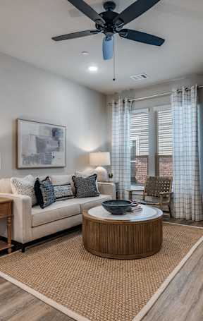 A living room with a white couch, a round coffee table, and a ceiling fan.
