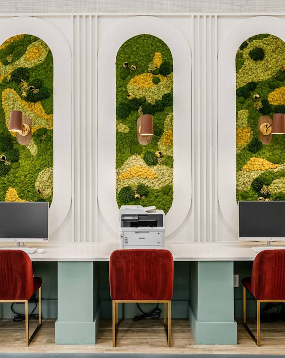 three desks with red chairs in front of a wall with a picture of a garden