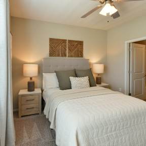 A bedroom with a large bed and a ceiling fan. at Hall Creek Apartment Homes, Arlington, Tennessee