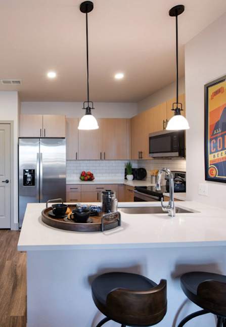 A kitchen with a white counter and brown chairs.